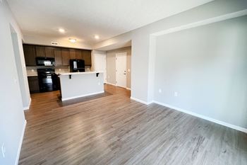 An empty living room and kitchen with wood flooring